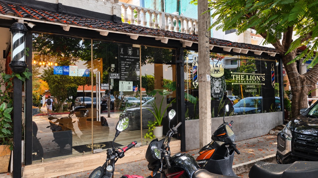 Fachada de The Lion's Barbershop en la 10 Avenida Norte con el letrero y postes de barbero